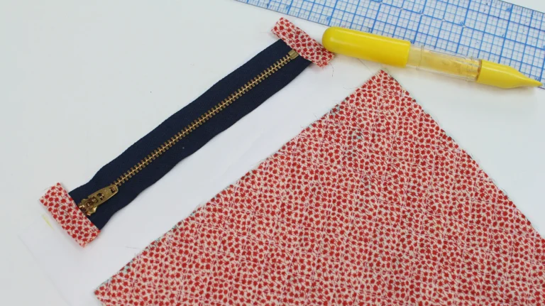 Quilted exterior fabric placed next to a zip with zipper tabs for a quilted wash bag.