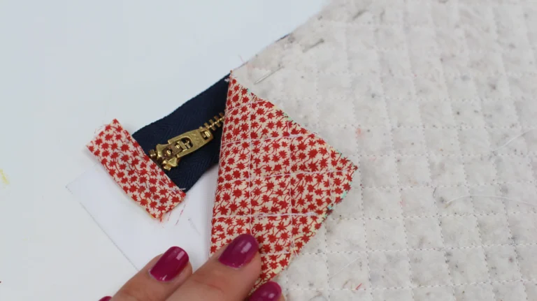 Close-up of a fabric zipper tab attached to a metal zip for a quilted wash bag.