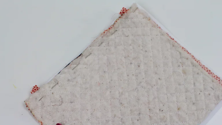 Quilted exterior and lining fabric layers pinned together with a zip ready to sew.