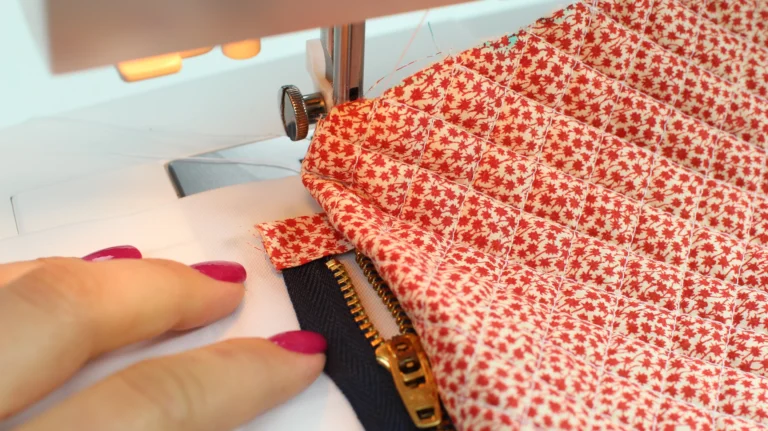Sewing a zip into a quilted wash bag using a zipper foot on a sewing machine.