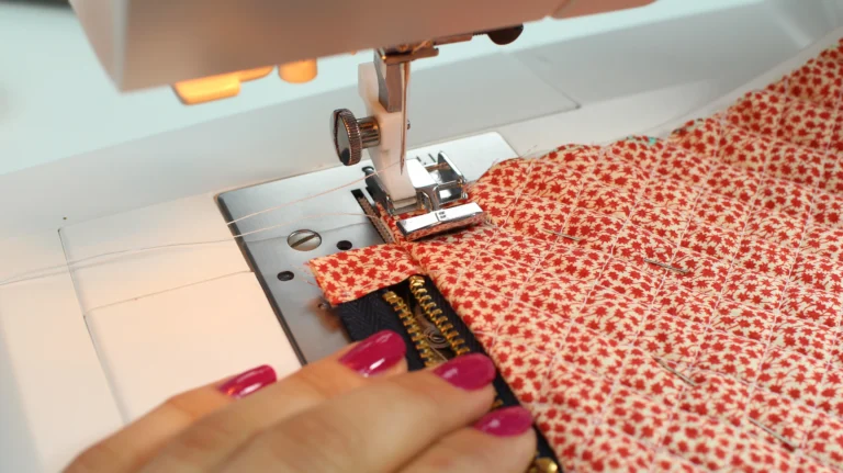 Sewing over fabric zipper tabs when assembling a quilted wash bag.