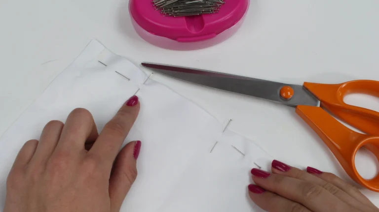 Pinning the lining fabric along the bottom edge of a quilted wash bag.