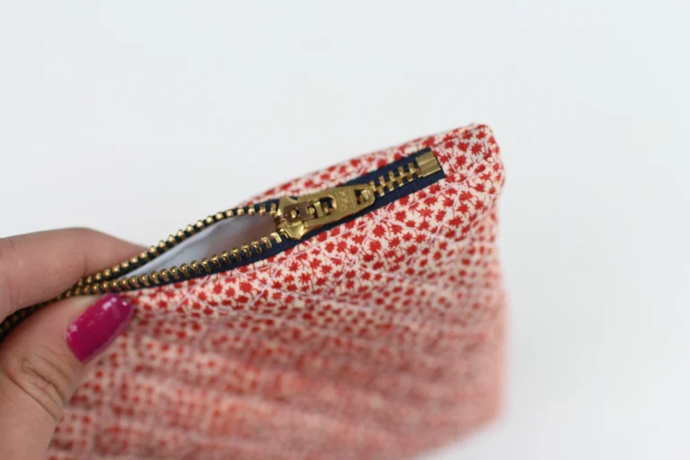 Finished zip end detail on a quilted wash bag with fabric zip tabs.