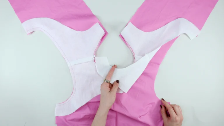 Showing the right sides of the facing and bodice material together, preparing to sew the armholes of an all-in-one facing and bodice with centre back seam