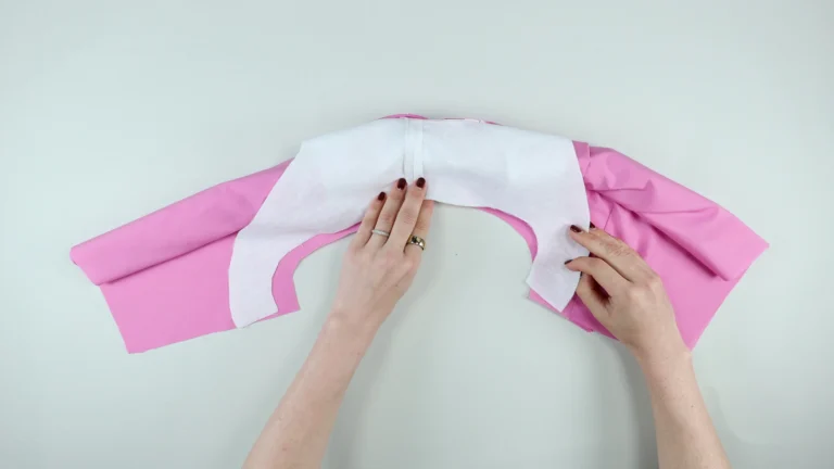 Position the facing and the outer right sides together, with the rolled fabric inside the shoulder seam, all-in-one facing with no centre back seam