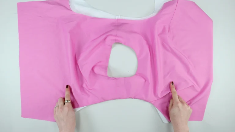 Outer fabric with the right side facing up. First side of the armhole sewn with the all-in-one facing, no centre back seam