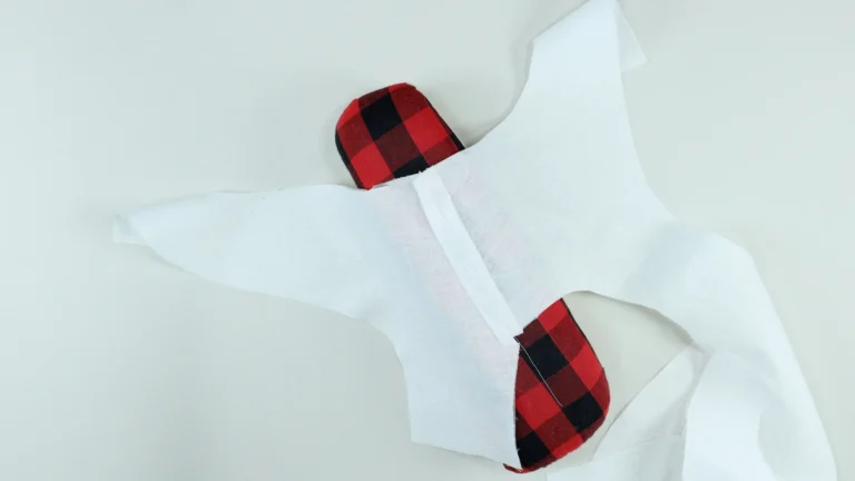 All-in-one facing pieces pressed open at the shoulder seam on a seam roll after being sewn together