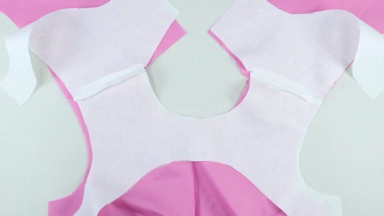 The facing and garment placed together, right sides of the fabric together, aligning the neckline