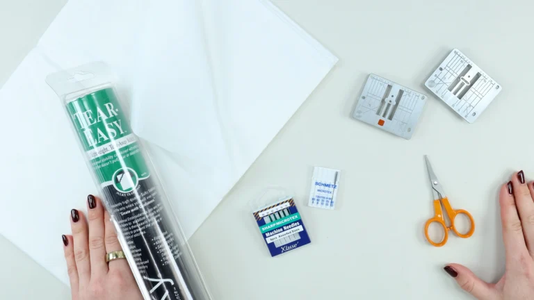 Tools needed to sew a baby hem including microtex needles, small scissors, tissue paper, tear-away stabiliser and straight stitch needle plates