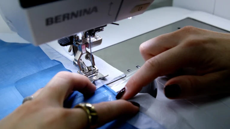 Sewing the final hem stitch on the baby hem, in a silk fabric with tissue paper to stabilse