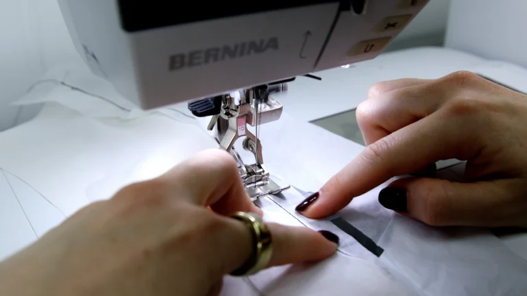 Sewing the final hem stitch on the baby hem, in a silk georgette fabric with tissue paper to stabilse