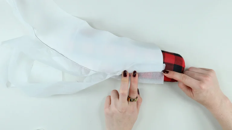 Folding the trimmed hem allowance towards the wrong side before sewing the final baby hem