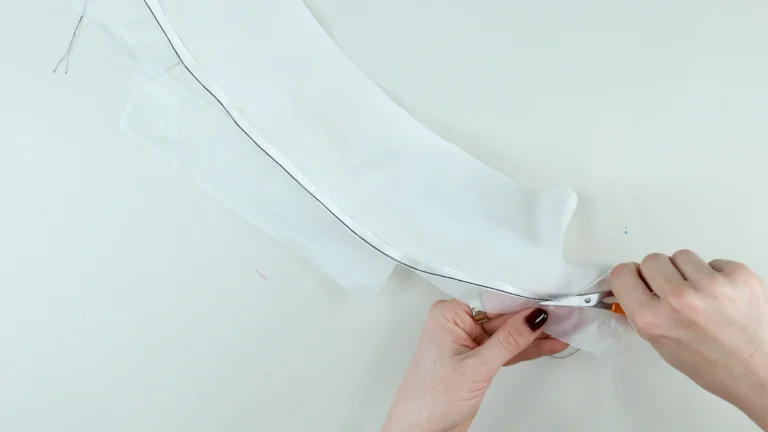 Trimming the excess fabric close to the stitching line when sewing a baby hem on lightweight fabric