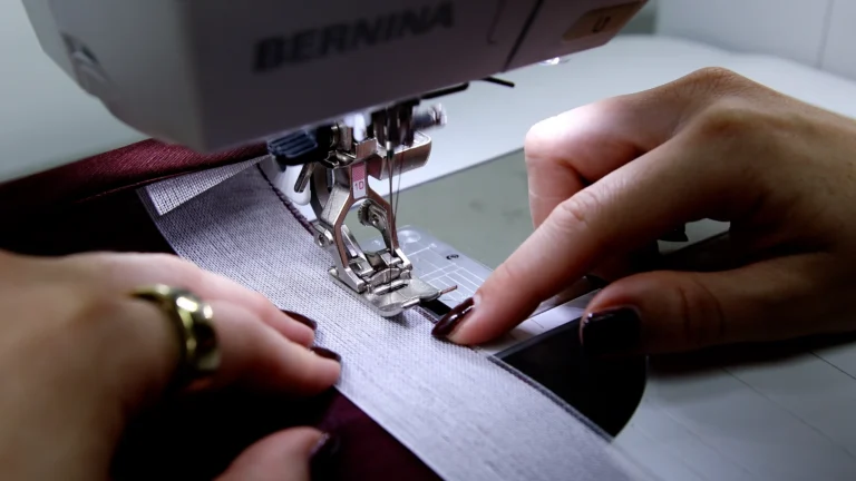 Sewing Ban-Rol onto the hem of a garment at the sewing machine, needle positioned next to warp threads
